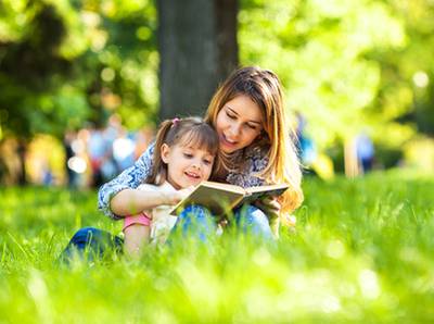 Mutter und Tochter mit Bilderbuch im Park