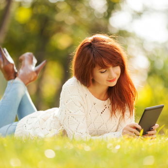 Frau liest eBook auf Wiese